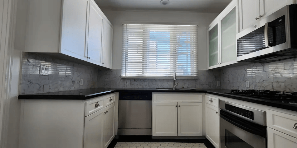 a kitchen with white cabinets and black countertops