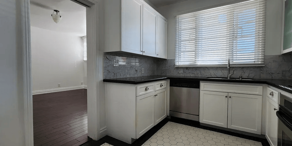 a kitchen with white cabinets and black countertops