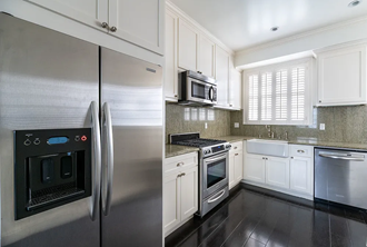 a kitchen with white cabinets and stainless steel appliances