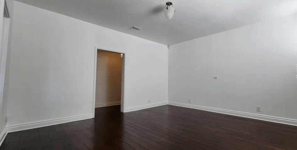 a bedroom with white walls and a dark wood floor