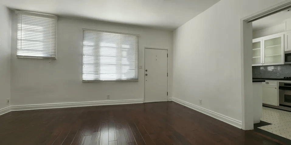 a bedroom with hardwood floors and white walls