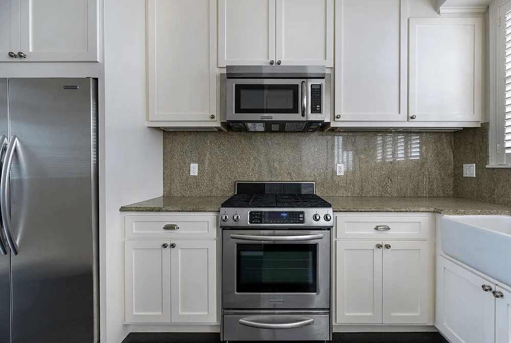 a kitchen with white cabinets and stainless steel appliances