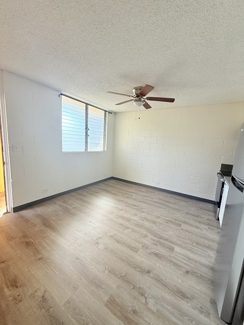 A room with a ceiling fan and a refrigerator.