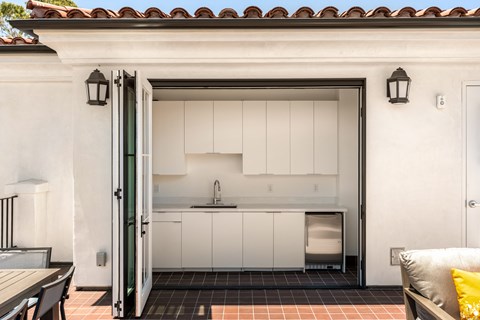 A kitchen with white cabinets and a black countertop is visible through an open door.