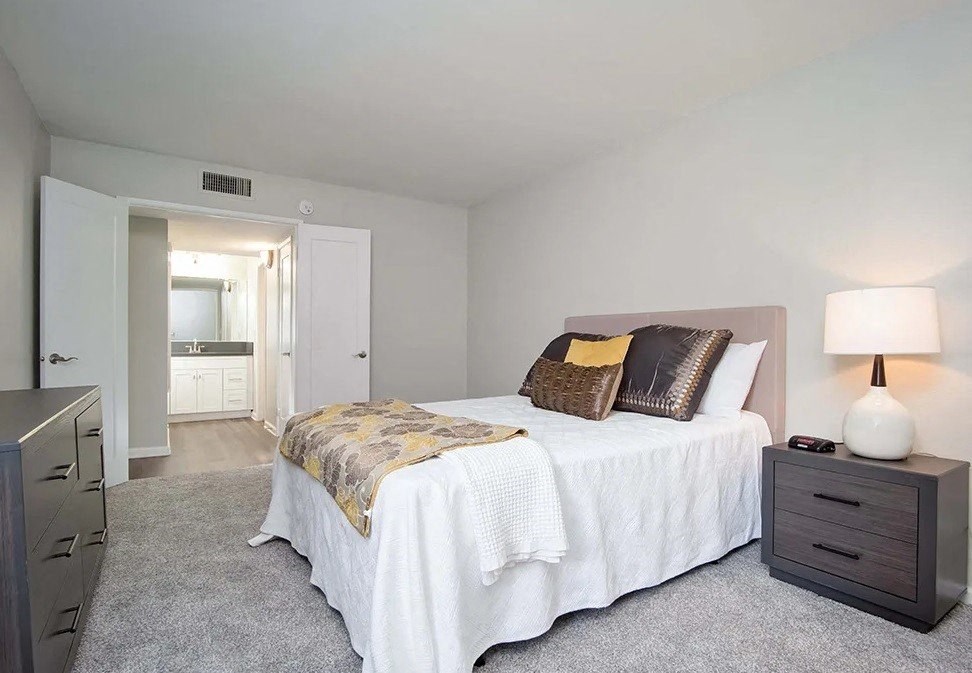 a bedroom with a bed and a hallway to a bathroom