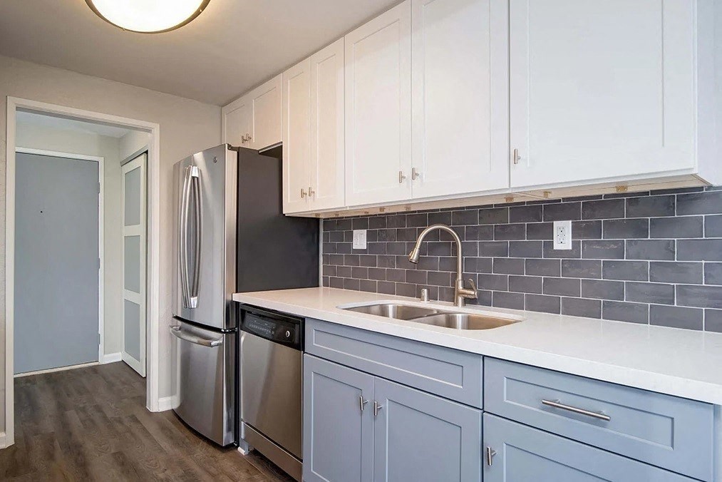 a kitchen with white cabinets and a stainless steel refrigerator