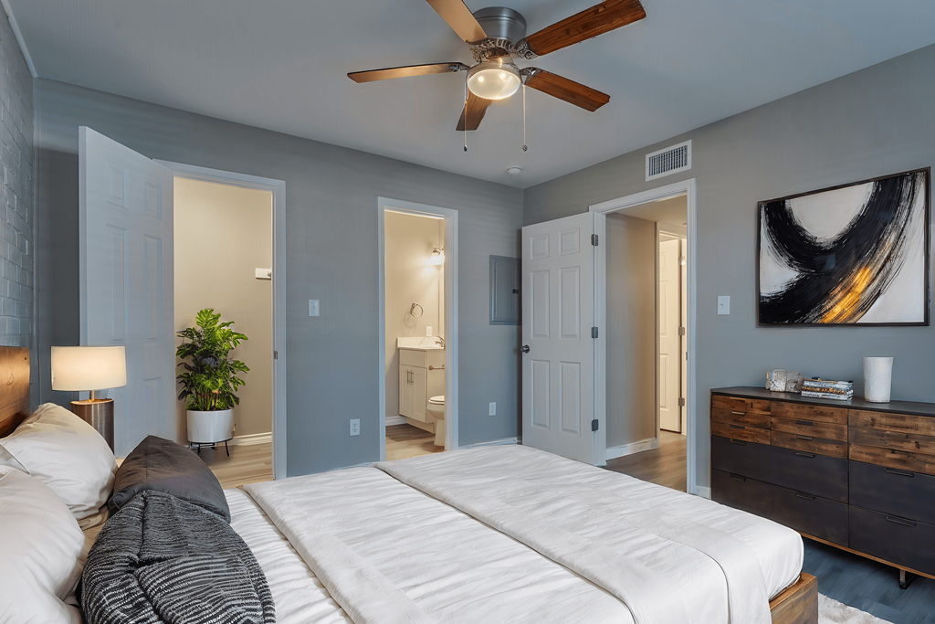 A bedroom with a white bed and a ceiling fan.
