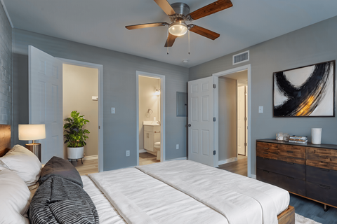 A bedroom with a white bed and a ceiling fan.