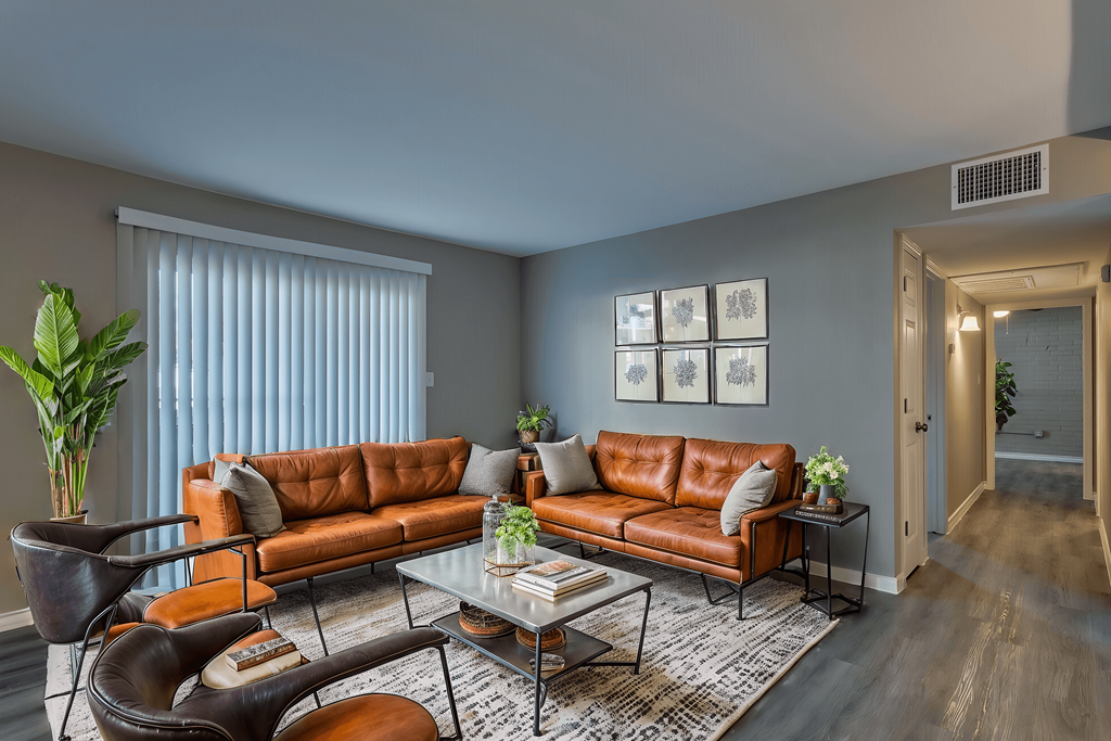 A living room with a brown leather couch and a glass coffee table.