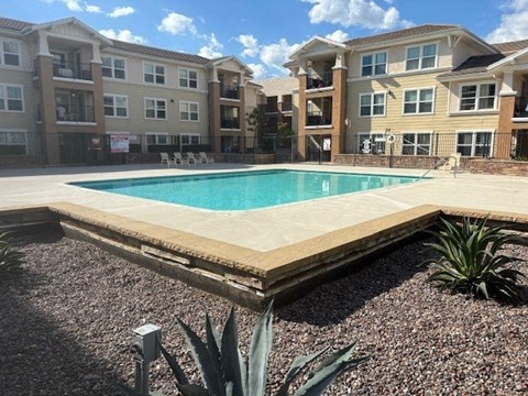A swimming pool surrounded by a fence and a building in the background.