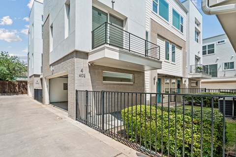 A modern two-story building with a balcony and a black fence in front.