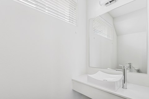 A white sink in a bathroom with a mirror and air conditioner above it.