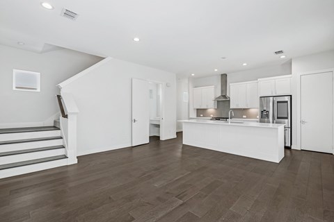 A modern kitchen with a staircase on the left side.