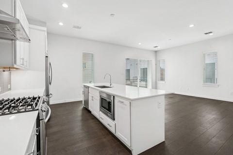 A modern kitchen with white appliances and wooden floors.