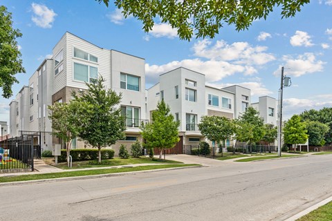 A row of modern houses with trees in front.