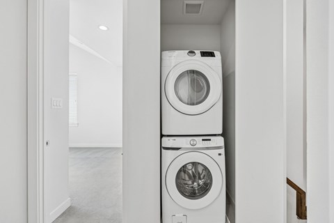Two washing machines stacked on top of each other in a laundry room.