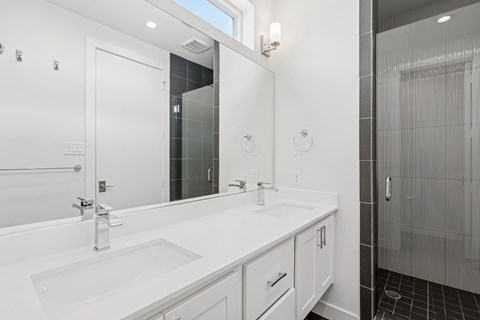 A white bathroom with a sink, mirror, and shower.