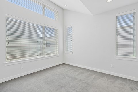 A room with two windows covered in blinds.