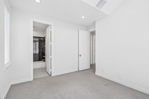 A white room with a carpeted floor and two open doors.
