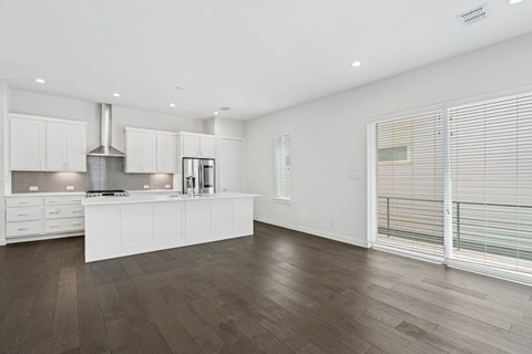 A modern kitchen with white cabinets and a wooden floor.