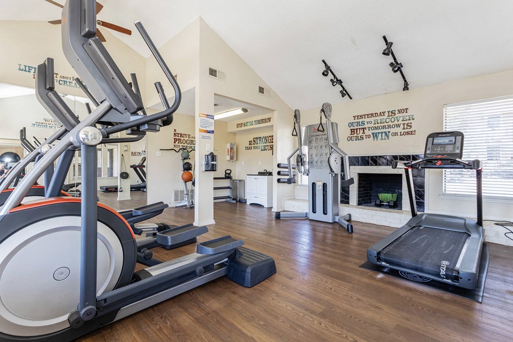 a gym with cardio equipment and a fireplace