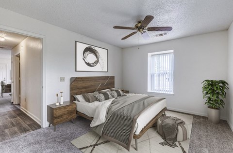 A bedroom with a bed, nightstand, and a ceiling fan.