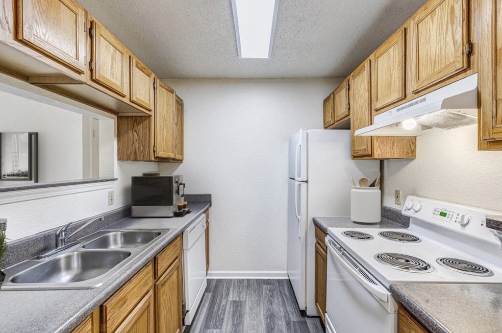 A kitchen with a white refrigerator, white stove, and wooden cabinets.