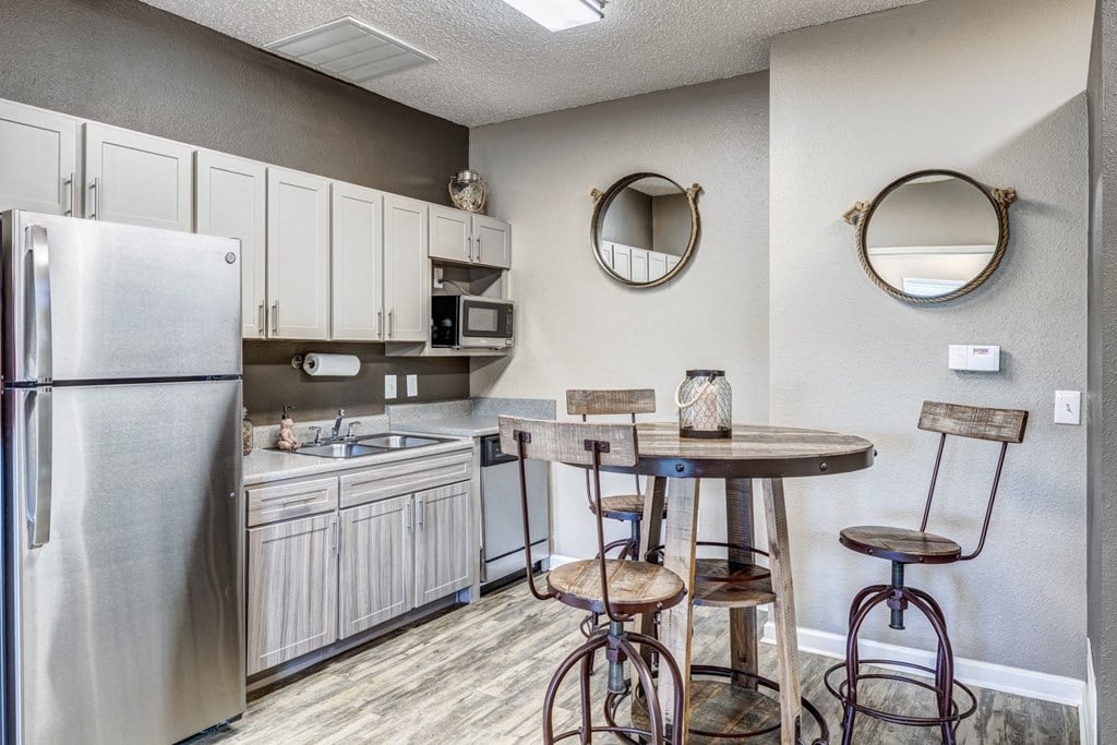 A kitchen with a refrigerator, sink, and bar stools.