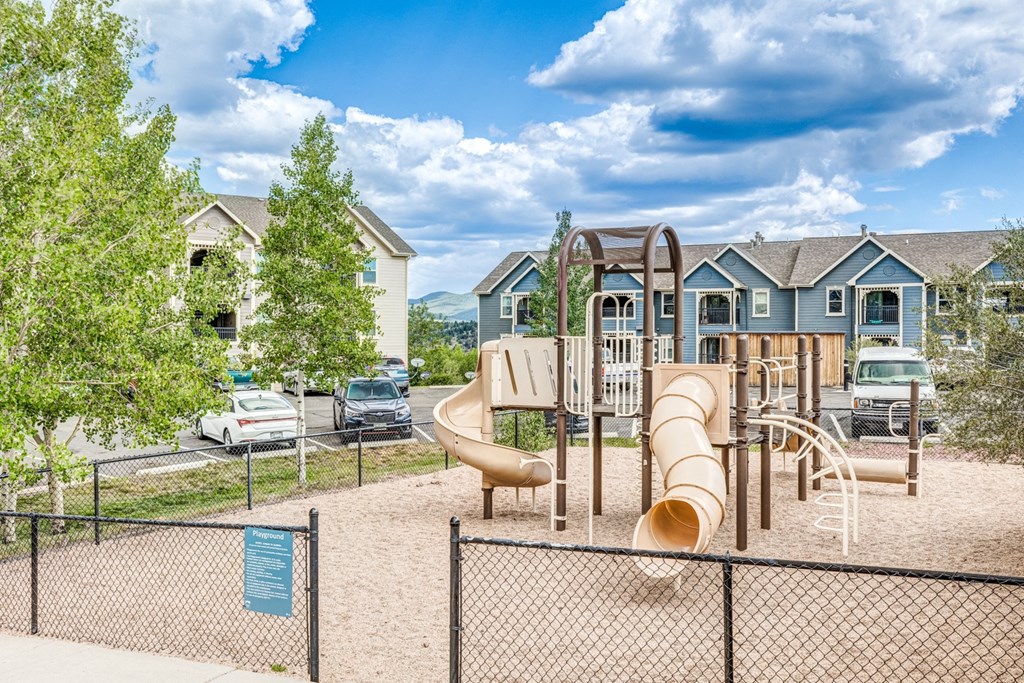 A playground with a slide and a fence in the foreground.