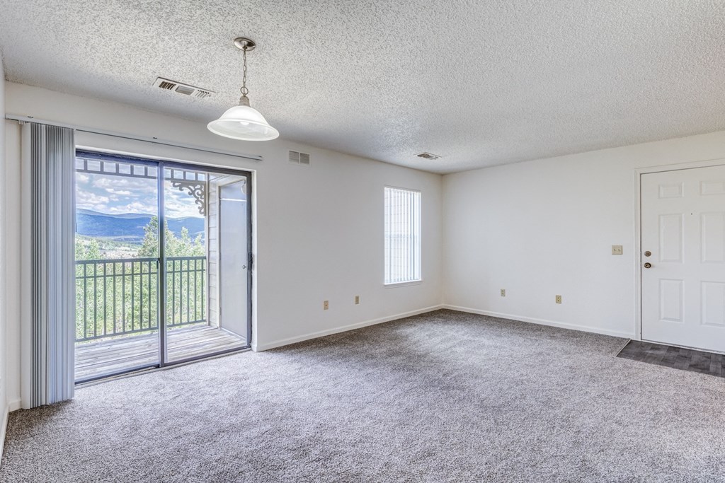 A spacious room with a sliding glass door leading to a balcony.