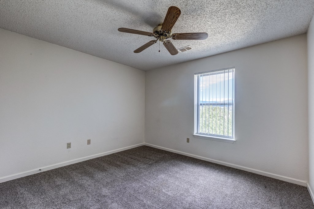 A room with a ceiling fan and a window letting in natural light.