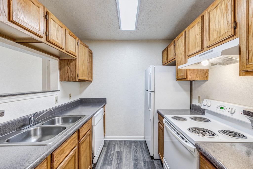 A kitchen with white appliances and wooden cabinets.