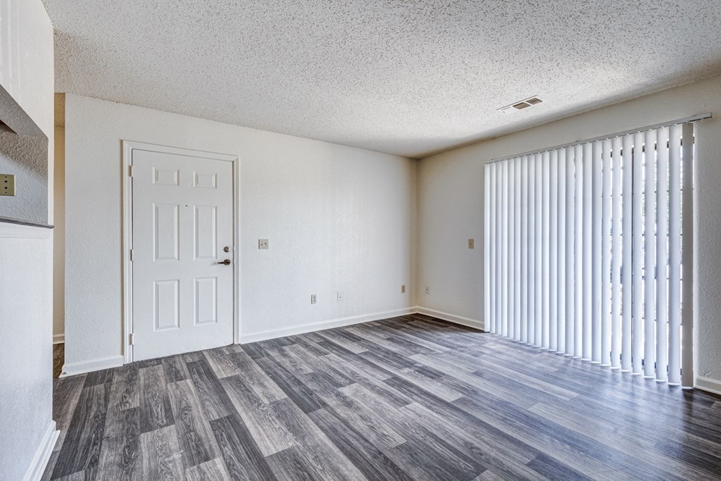 A room with a white door and a window with white blinds.