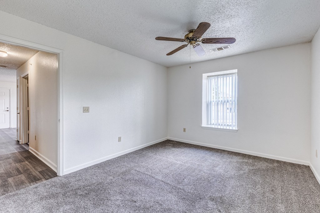 A room with a ceiling fan and a window with blinds.