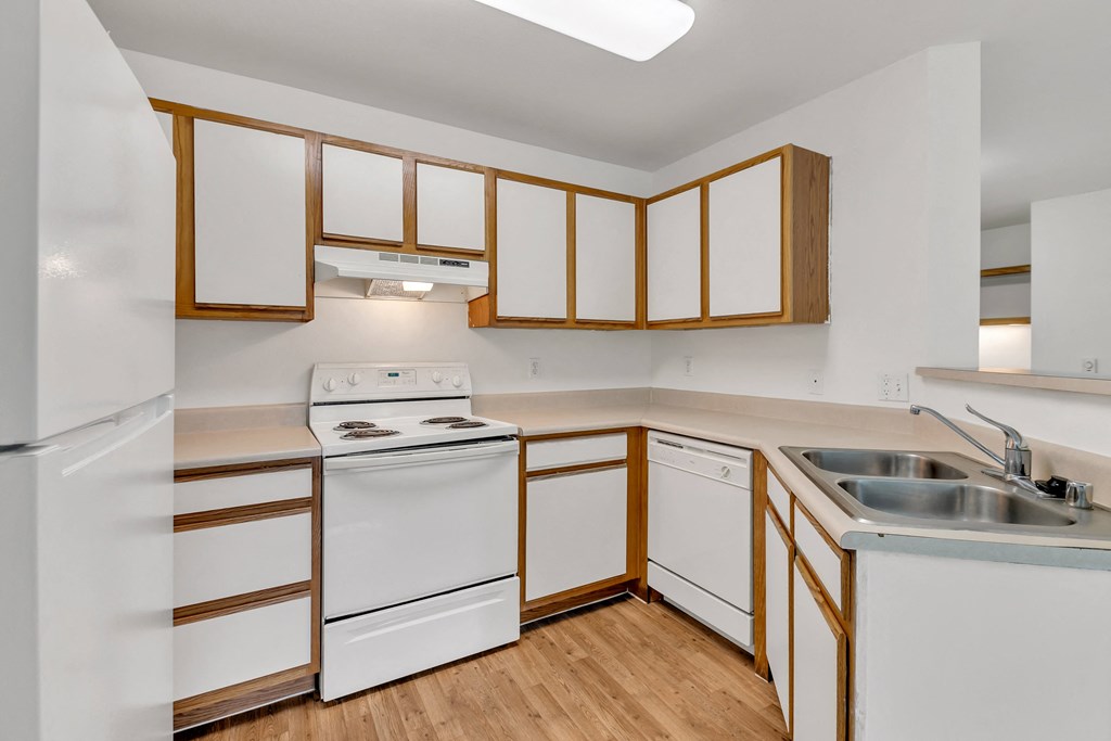 an empty kitchen with white appliances and wooden cabinets