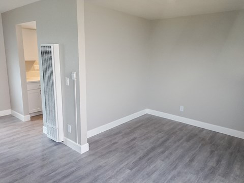 an empty living room with a heater in the corner