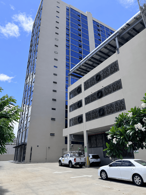 A white car is parked in front of a building with a blue sky in the background.