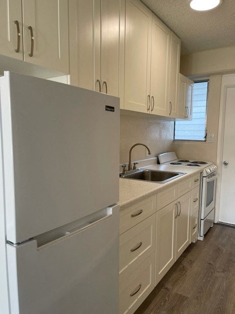a white kitchen with a refrigerator and a sink