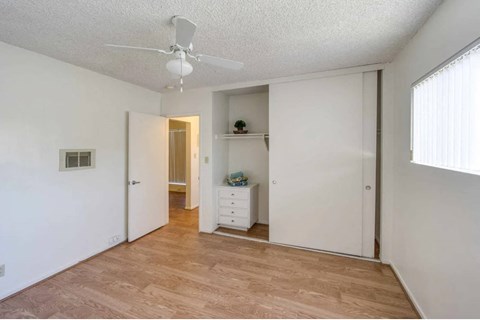 an empty living room with a ceiling fan and a closet