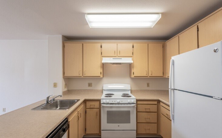 A kitchen with a white refrigerator, sink, and stove.