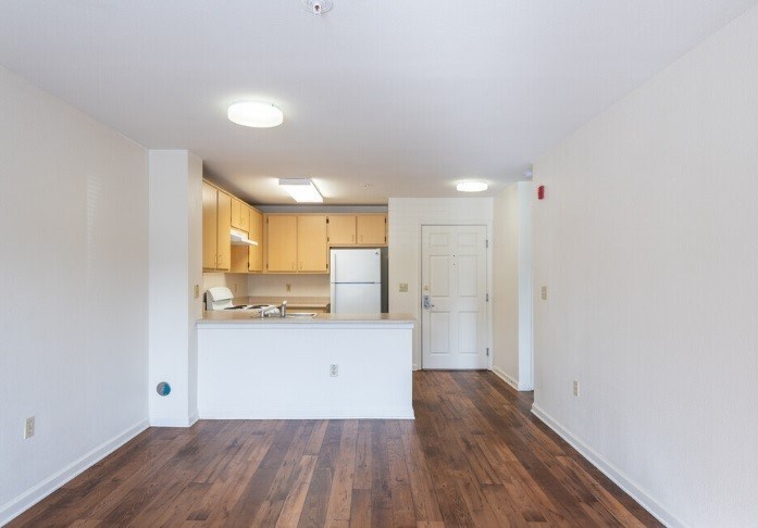 A kitchen with white cabinets and a white island in the middle of a room with wooden floors.