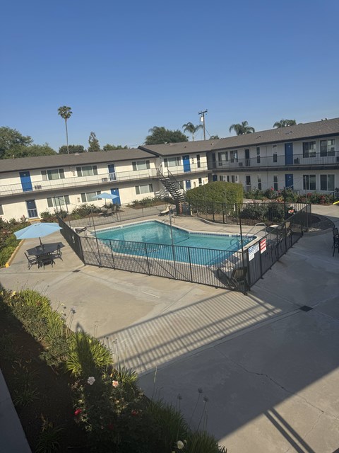 A pool surrounded by a fence and a building in the background.