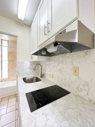 a kitchen with white cabinets and white marble countertops
