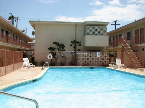 A pool in front of a building with a tree in the background.