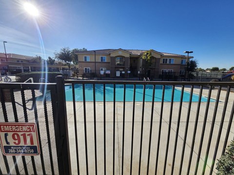 A pool with a fence that has an emergency 911 sign on it.