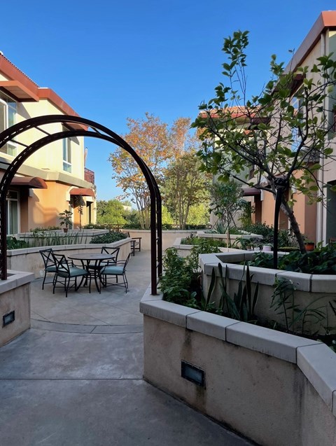 A patio with a table and chairs is surrounded by a wall and a tree.