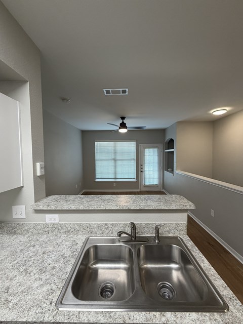 A modern kitchen with a granite countertop and stainless steel sink.
