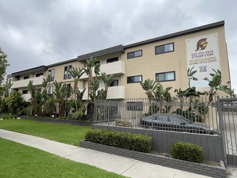A building with a sign that reads "Now Styling" is surrounded by greenery.