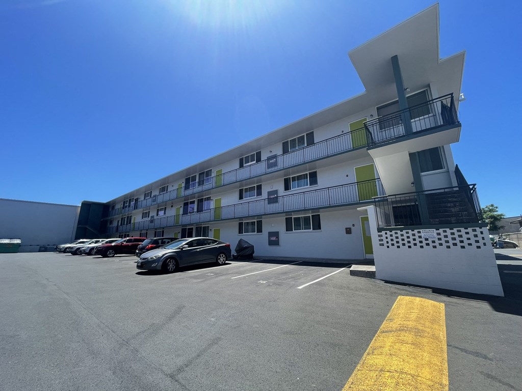 a large white apartment building with cars parked in front of it