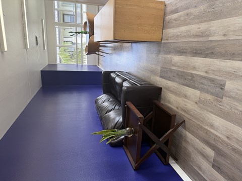 A blue cushioned bench with a black leather cushion and a wooden table.